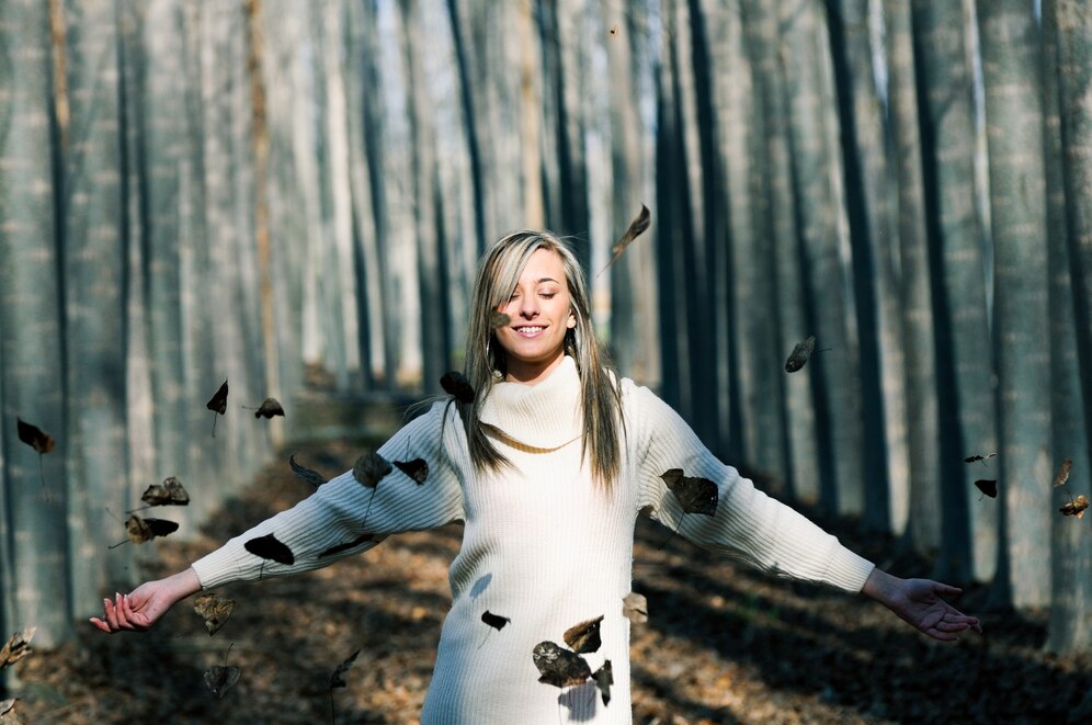 a woman in a white sweater with her arms out in the air